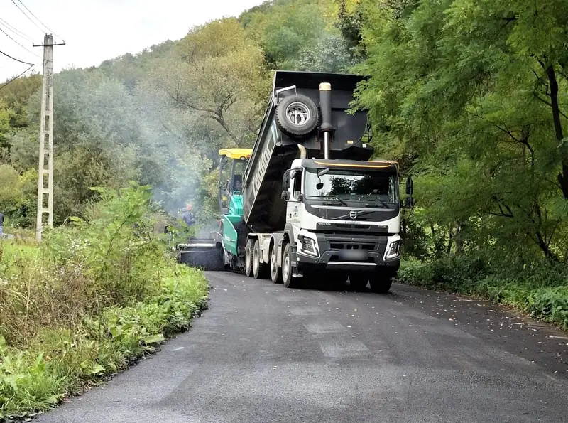 Volvo billencs tölti az aszfaltot a finisherbe egy erdős szakaszon